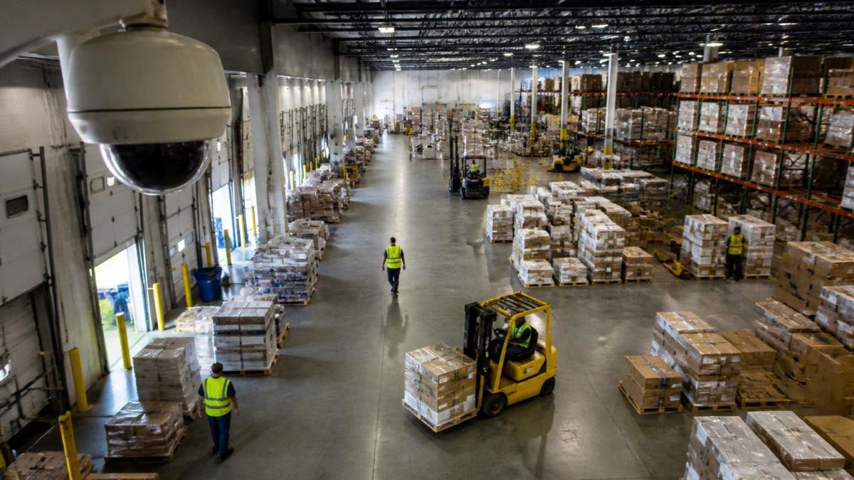 Ceiling camera monitors workers and forklifts for AI threat detection for warehouses in a busy facility.